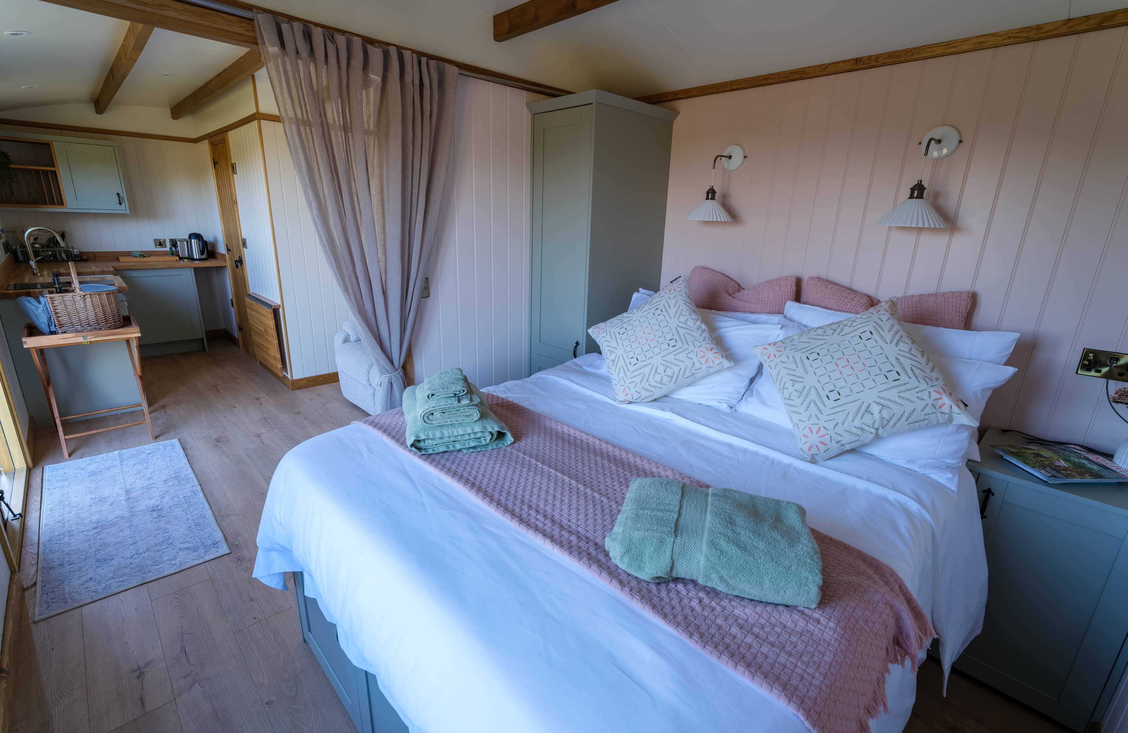 King-size bed featuring white painted paneling and muted blush pink throws